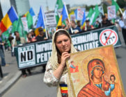A Romanian woman holds an Orthodox icon as she marches with Romanian flag during a protest against incoming Gay Pride in Bucharest on June 8, 2013.