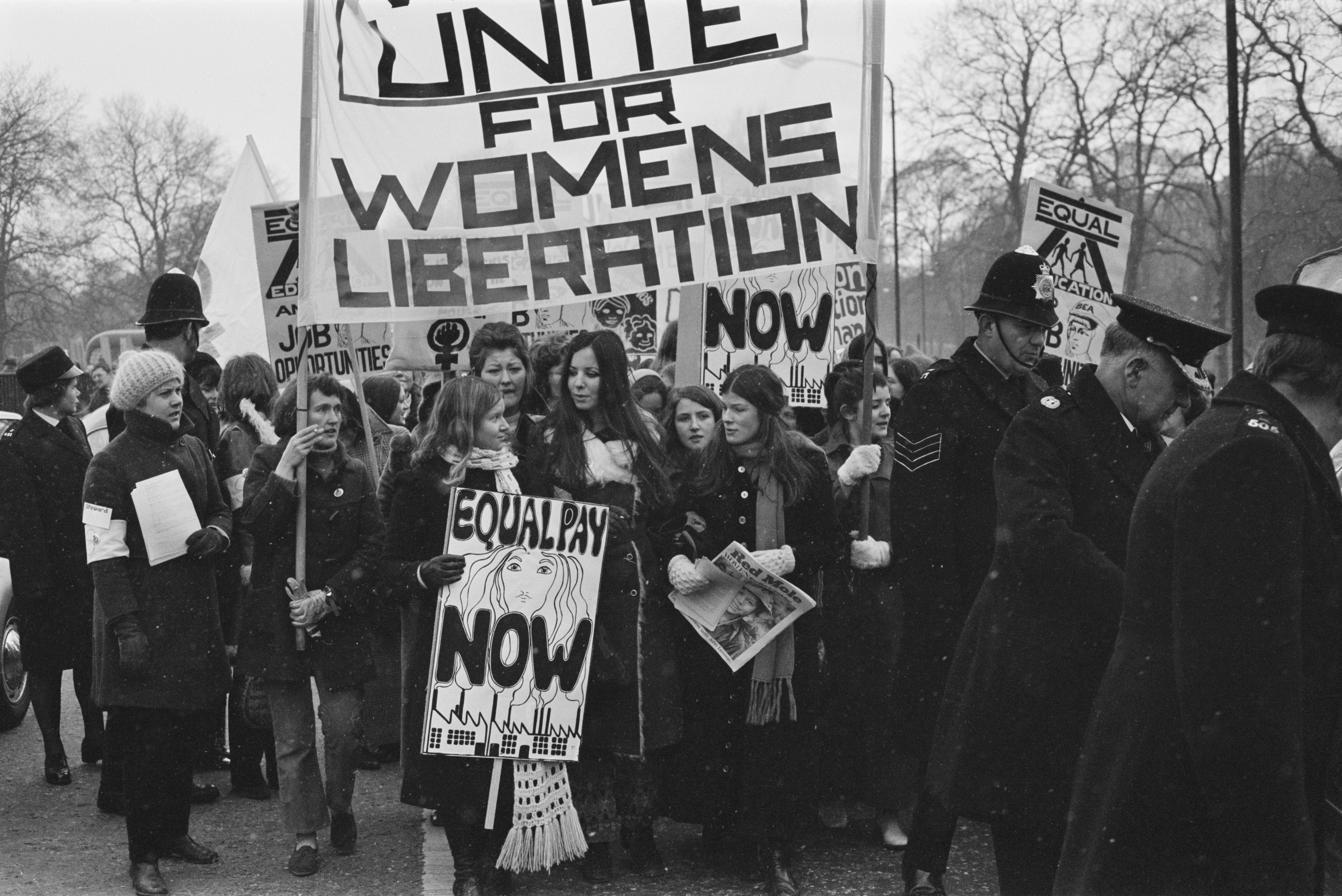 Members of the National Women's Liberation Movement, on an equal rights march from Speaker's Corner to No.10 Downing Street, to mark International Women's Day, London, 6th March 1971. One woman is carrying a placard reading 'Equal Pay Now'. On the right, a woman is holding a copy of the Trotskyist publication 'Red Mole'.