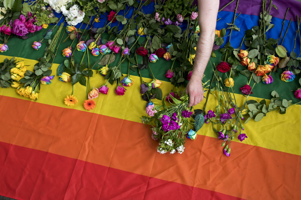 Demonstrators lay roses on a rainbow flag as they protest over an alleged Chechnya anti-gay purge outside the Russian Embassy in London on June 2, 2017.