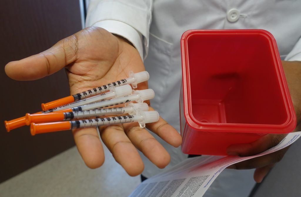 A doctor holds needles