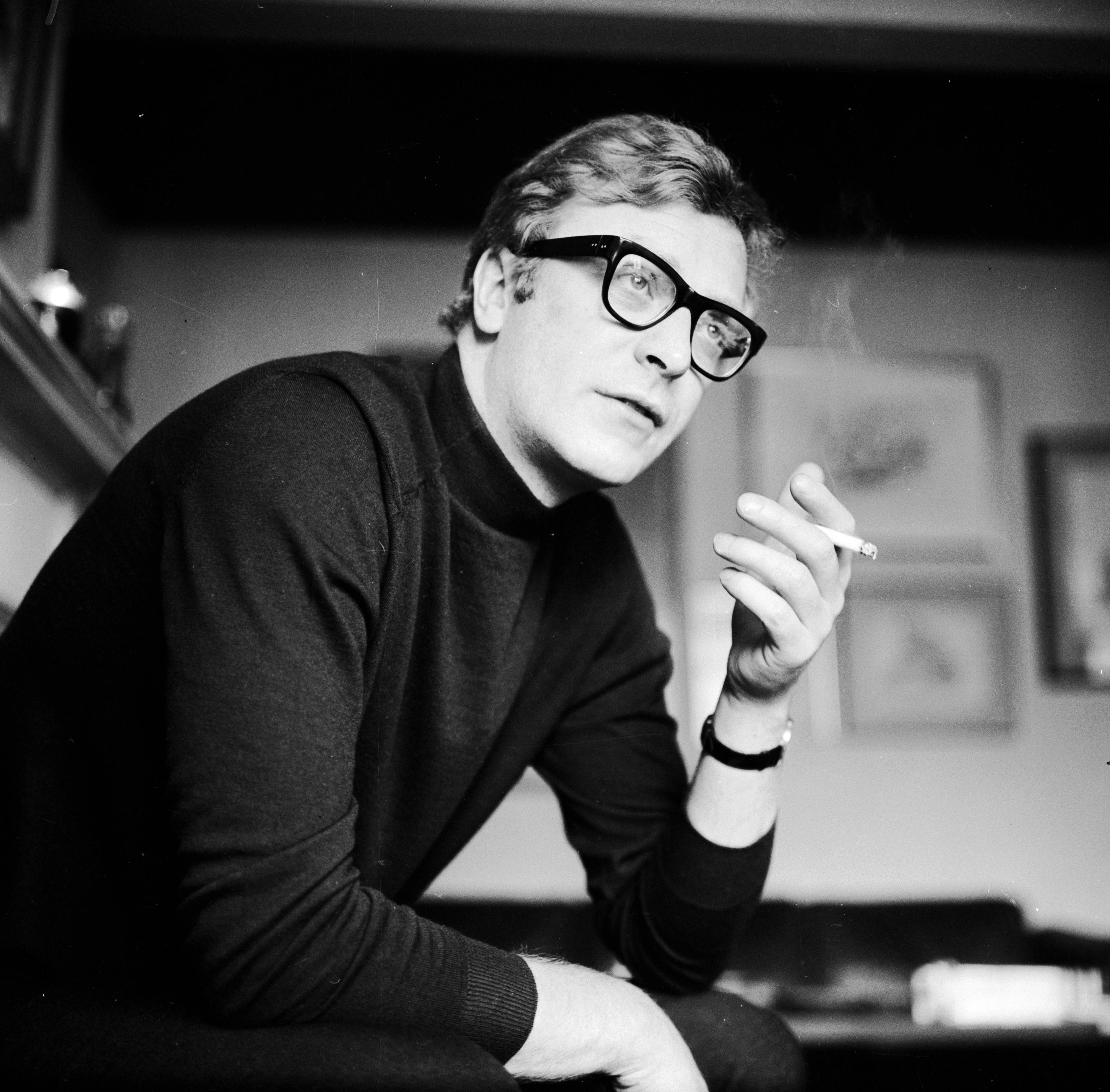 English actor Michael Caine smoking a cigarette.