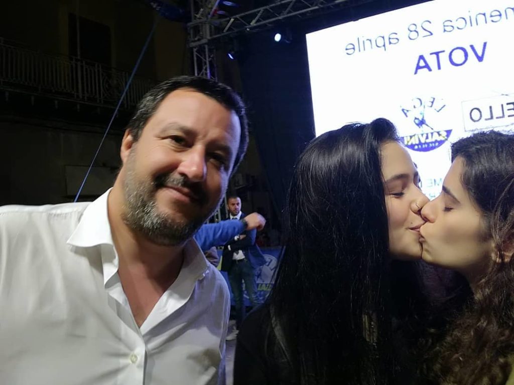 Matteo Salvini next to two women kissing.