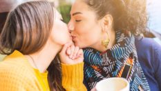 Lesbian couple kissing at a cafe