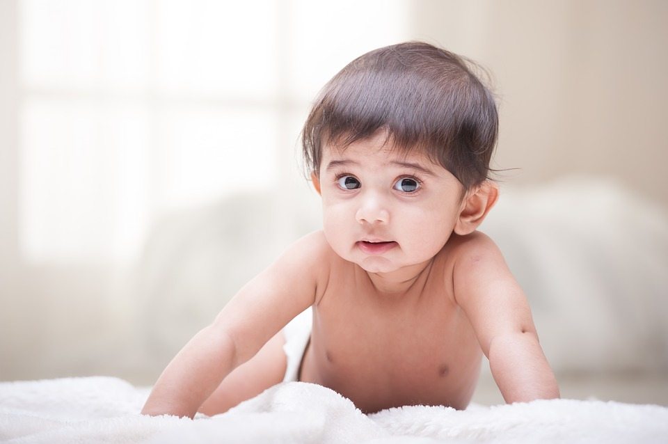 A baby crawling on a blanket. (Creative Commons)