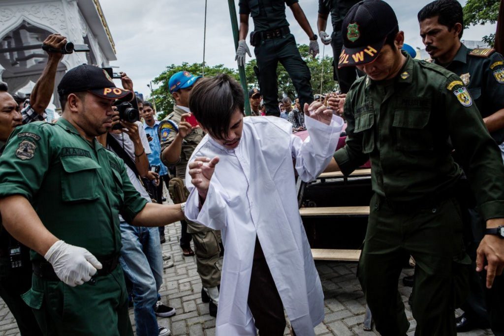 A man in Indonesia is escorted by the Sharia police after get caning in public from an executor known as 'algojo' for having gay sex, which is against Sharia law