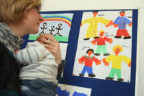 A woman holding a baby looking at drawings. She is at Germany's first gay parent counselling centre.