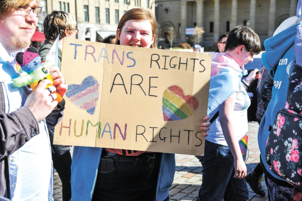 A participant is seen holding a placard during the 2019 Trans Pride march in Dundee.