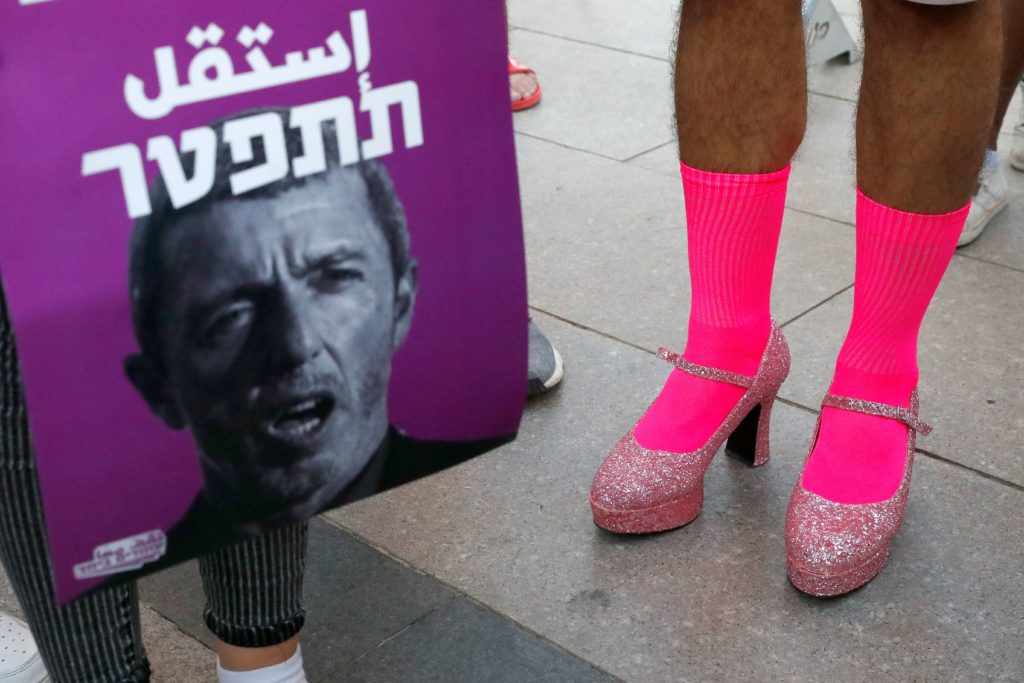 Members of the LGBT community hold a banner reading in Hebrew 'A homophobic Racist Has to Quit' during a rally against Israel's Education Minister Rafi Peretz following his remarks on gay conversion therapy, in the Israeli coastal city of Tel Aviv on July 14, 2019.