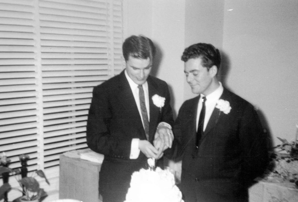 Two grooms cutting their wedding cake