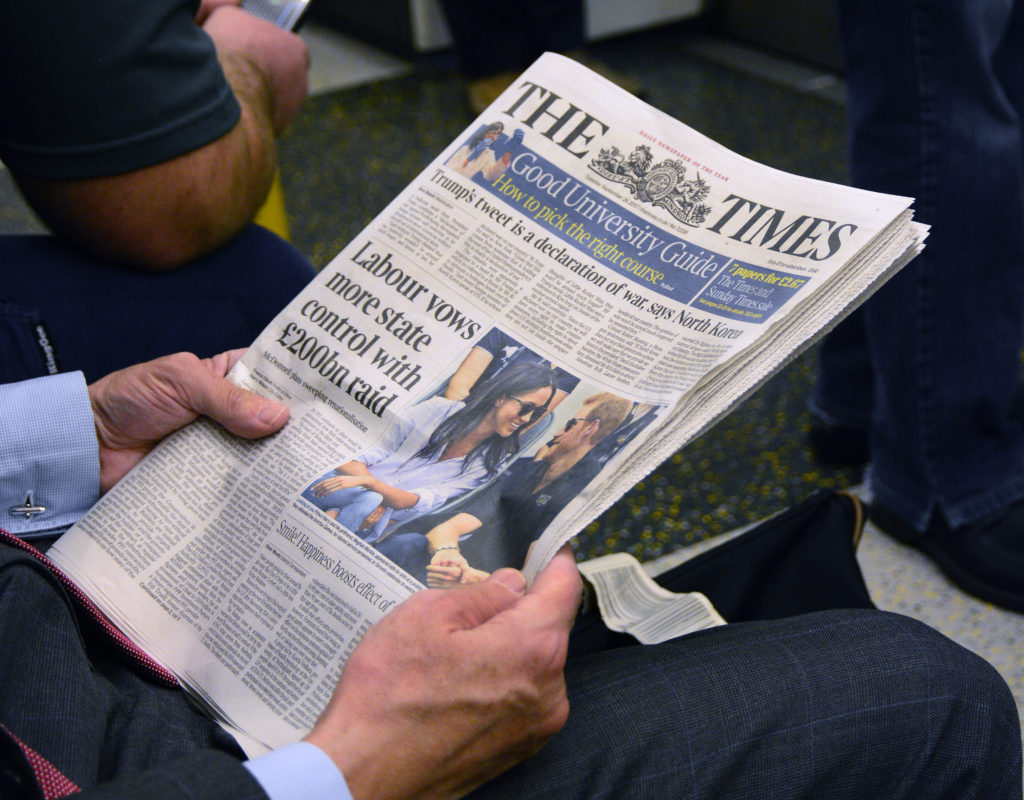 A man reads The Times newspaper as he rides the tube in London