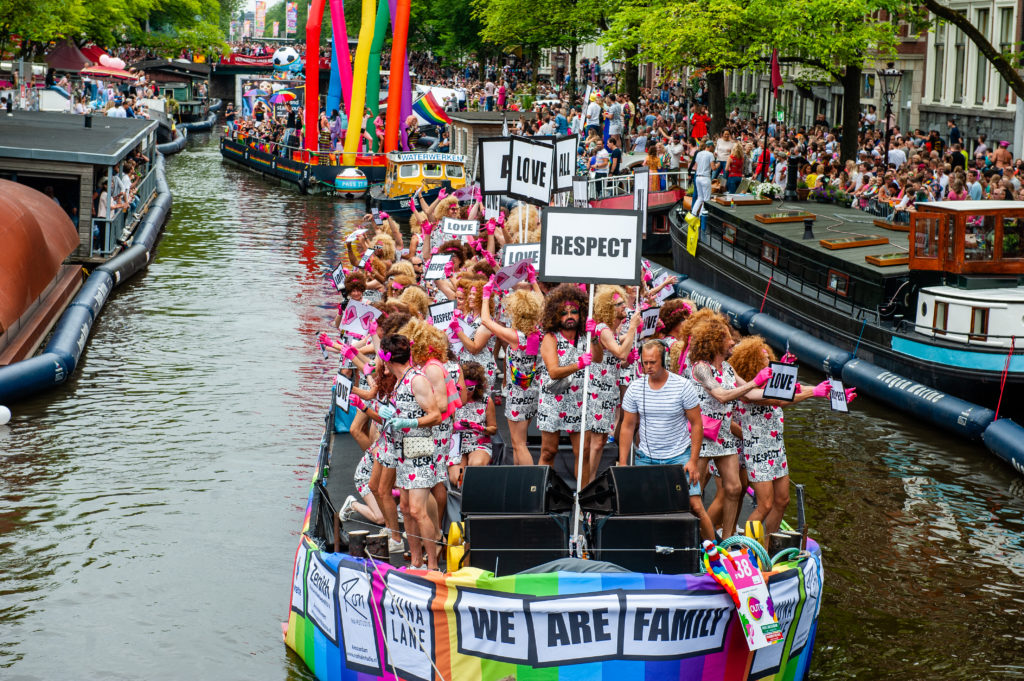 A group of drag queens are seen on a boat while holding placards saying Respect during the parade.