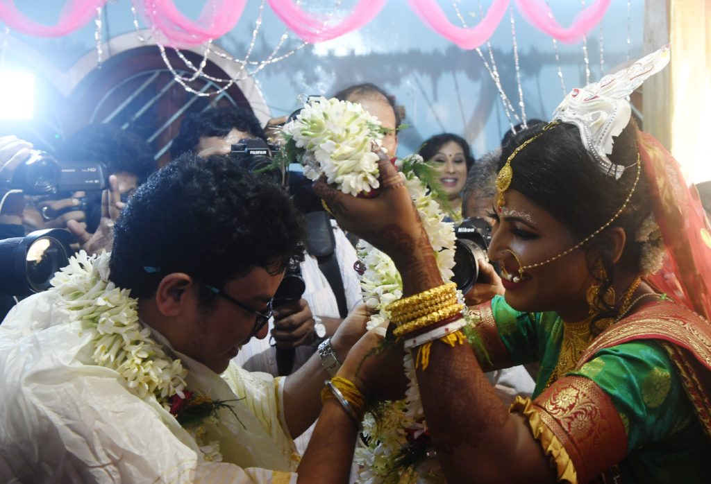 A bride places a garland over her groom's head