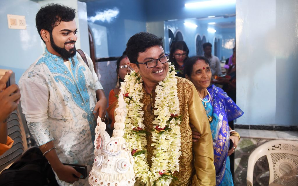 Trans groom Dipan arriving at his wedding, smiling.