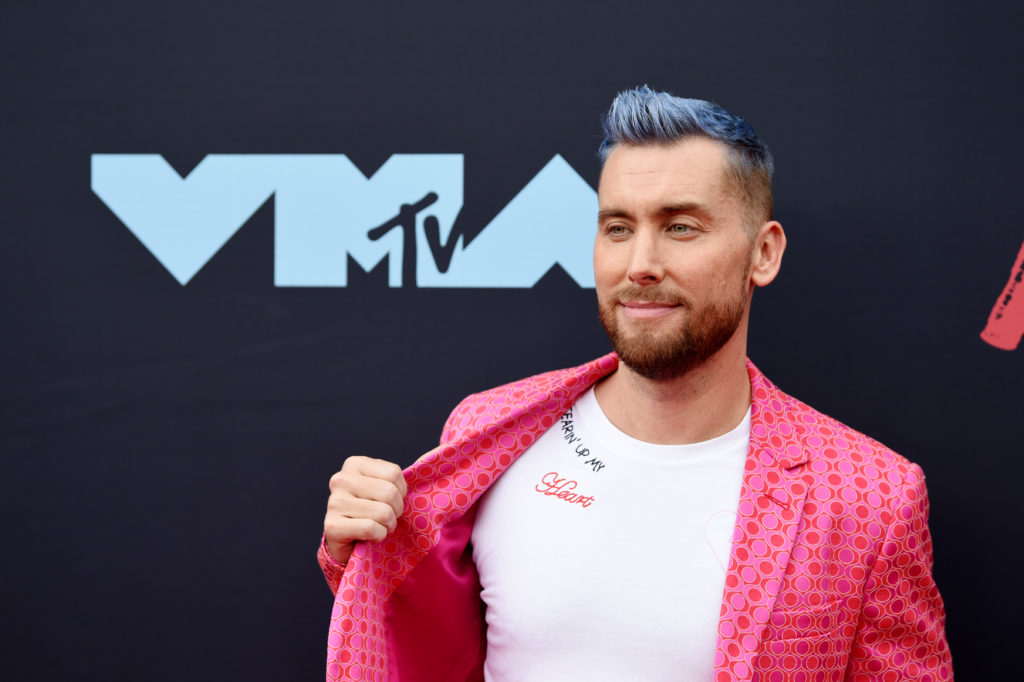 Lance Bass pulling his jacket aside to show the 'Tearin' Up My Heart' message on his t-shirt
