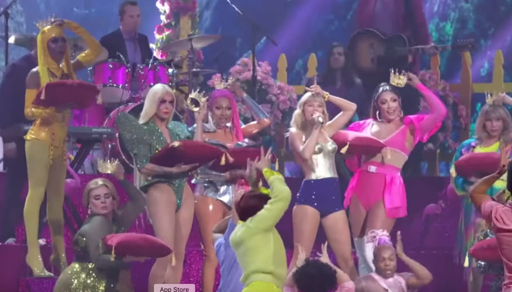 Taylor Swift holding a crown to her head flanked by drag queens including Tatianna and Jade Jolie