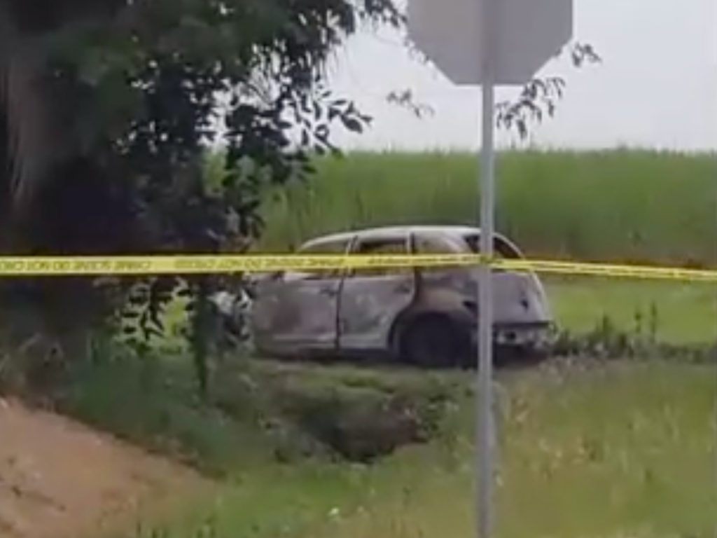 A burned-out car surrounded by blackened grass