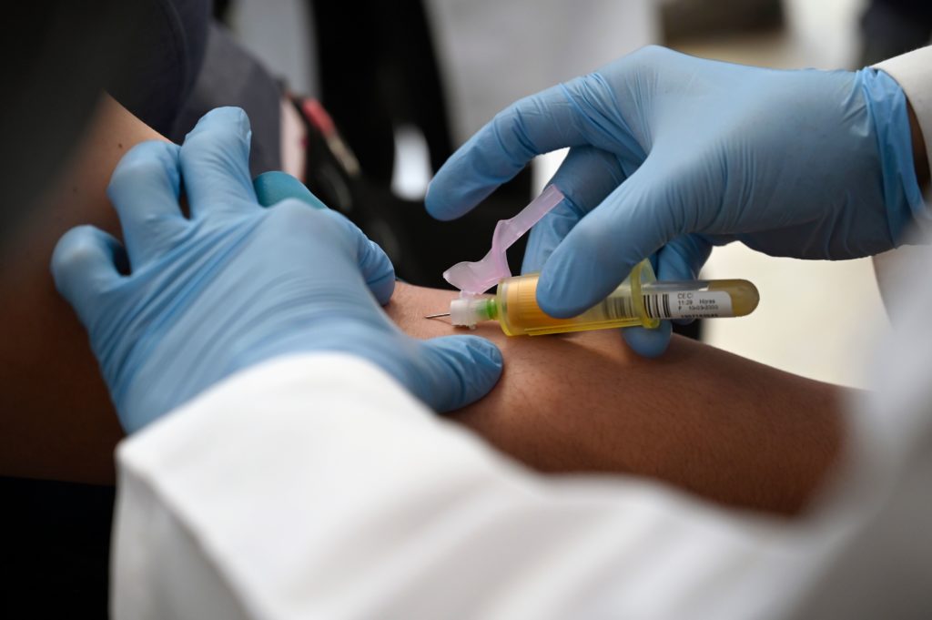 A technician extracts blood from a patient for an HIV test.