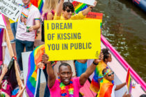 A black man holds a placard on the boat of Amnesty International during Amsterdam's famous canal pride parade