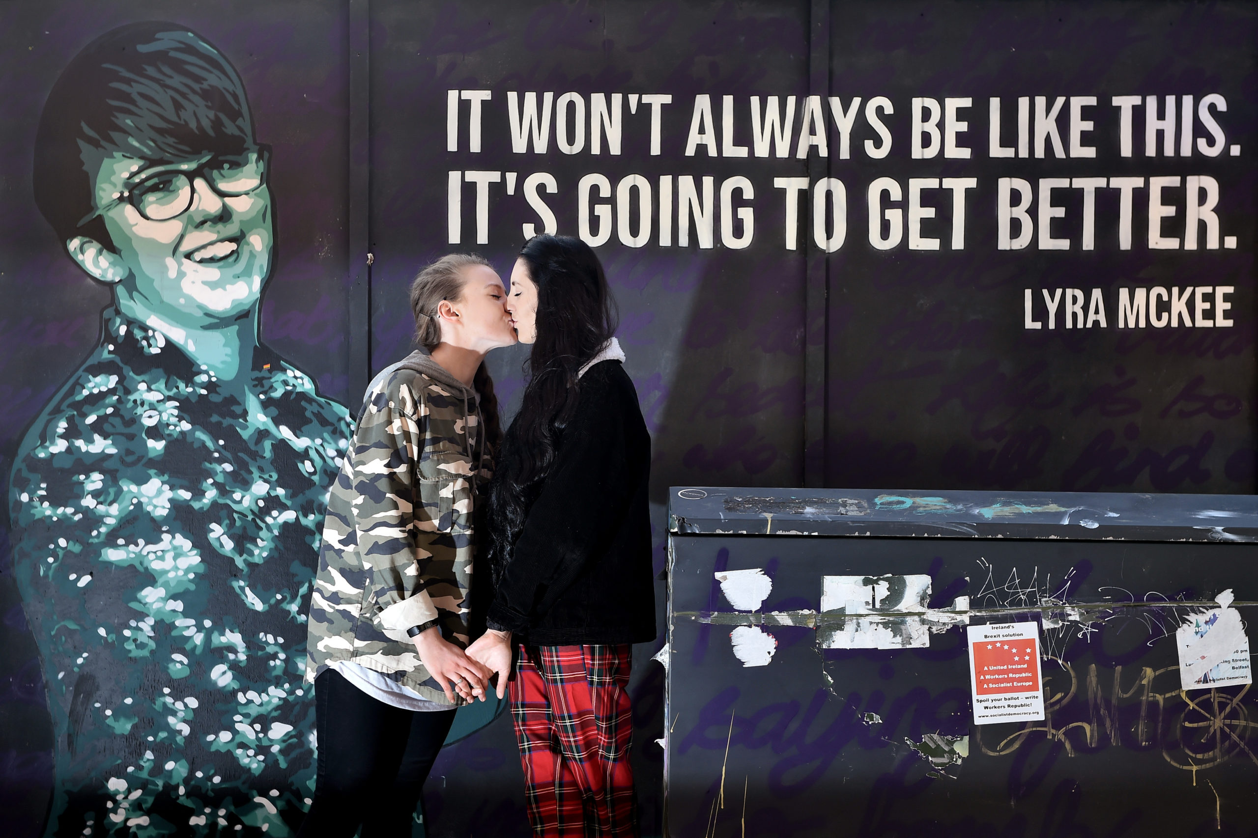 Robyn Peoples and Sharni Edwards, Northern Ireland's first same-sex couple to be legally married, kiss as they pose in front of the Lyra McKee mural in February 2020