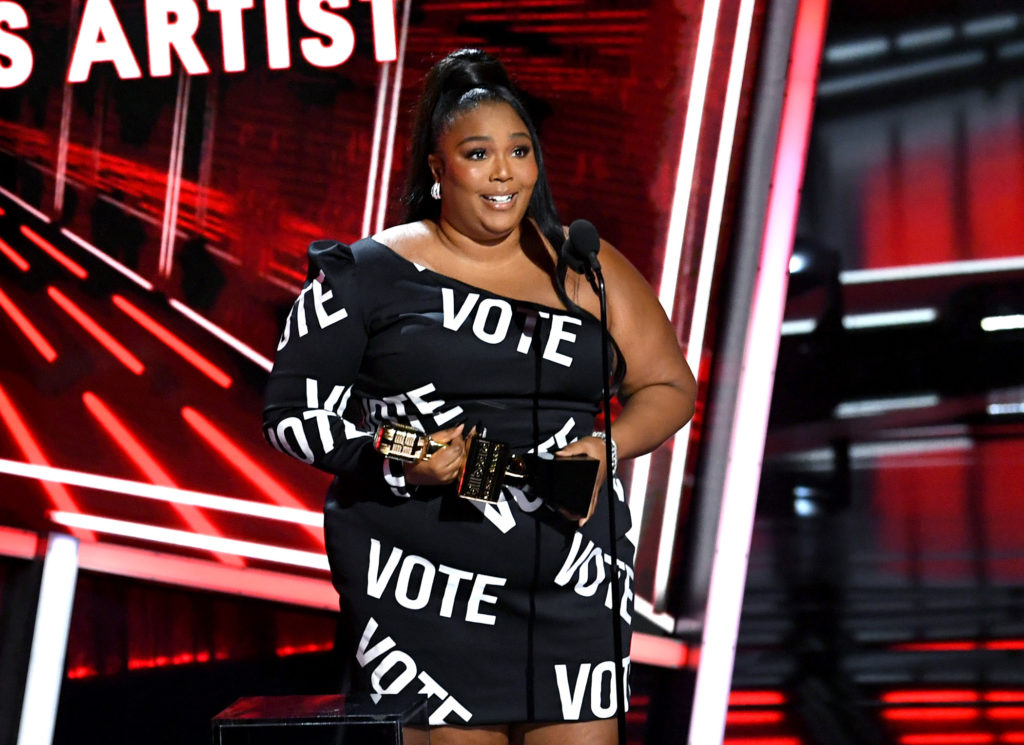 Lizzo in a black dress with the word VOTE in bold white text all over