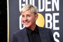 Ellen DeGeneres smile while wearing a grey suit jacket
