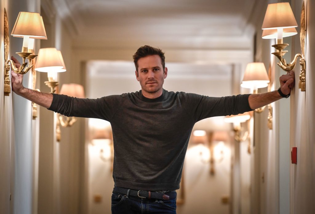 Armie Hammer stretches his arms outwards towards the corridor walls