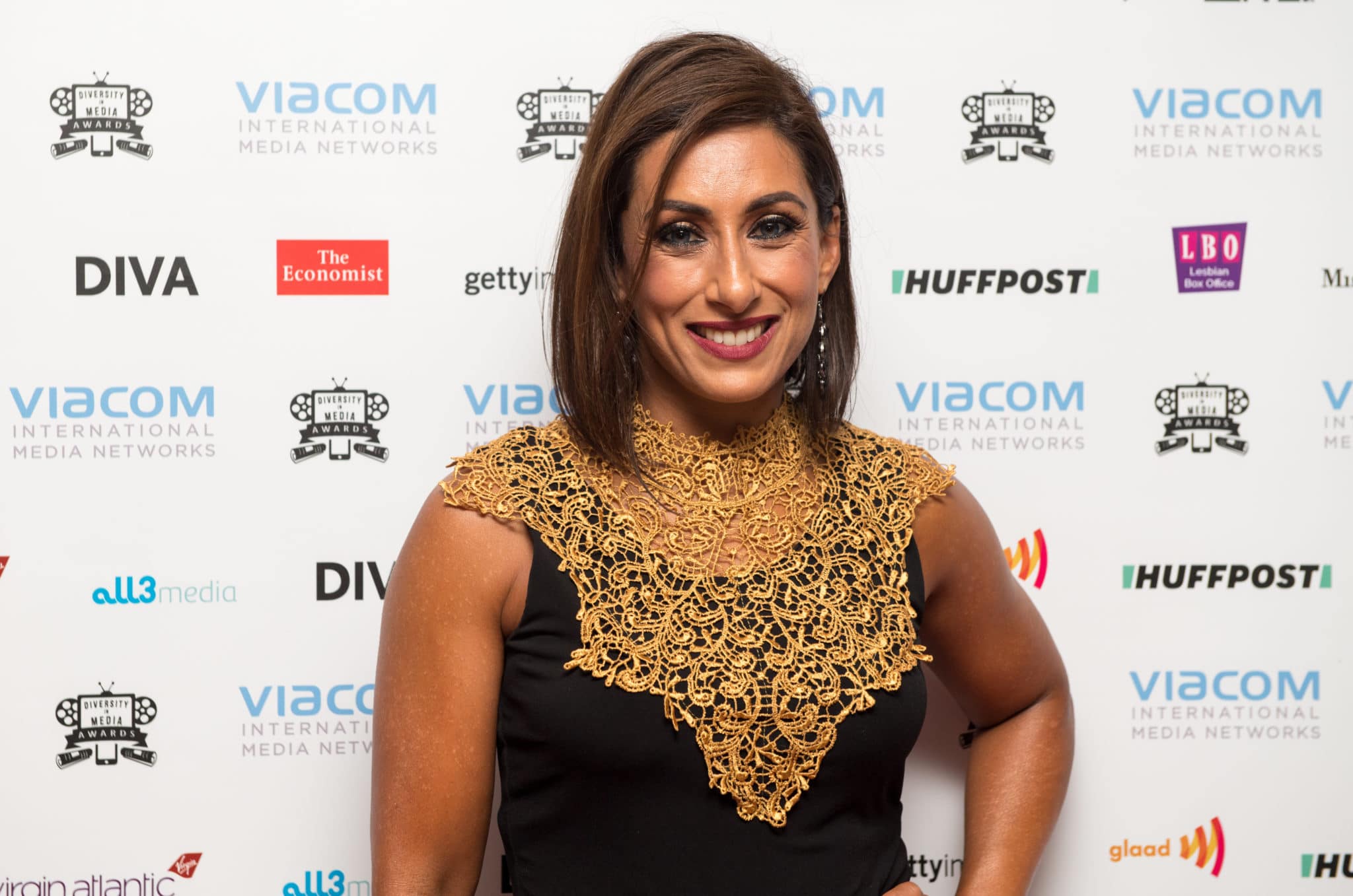 Saira Khan poses in a gold and black dress