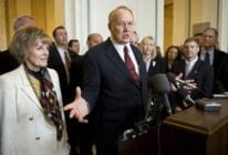 James Dobson in a red tie and black suit standing by his wife Shirley Dobson (L)