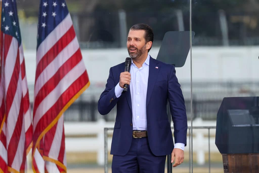Donald Trump Jr speaking in front of American flags