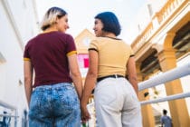 Portrait of lovely lesbian couple spending time together and holding hands at the street