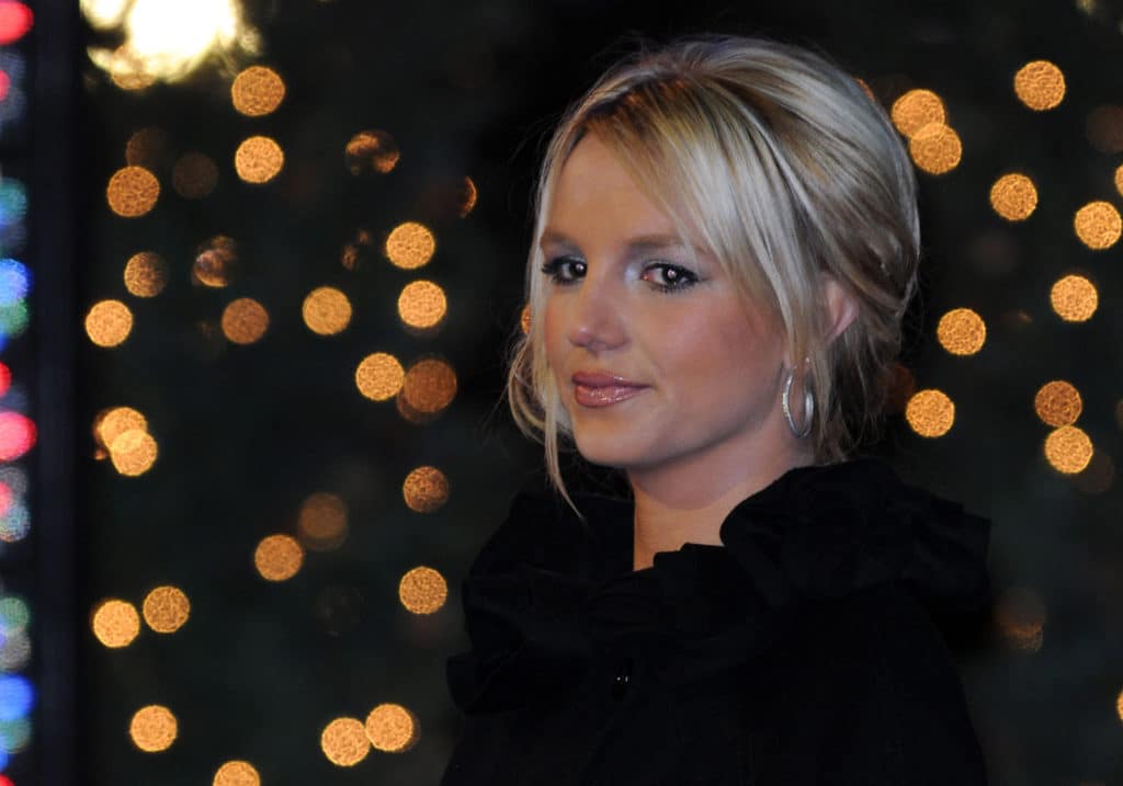 Britney Spears faintly smiles against a backdrop of blurred-out lights