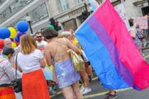 Parade goers with one holding the Bisexual Pride flag during Pride in London 2019