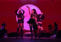 Ariana Grande and dancers on stage, drenched in pink lighting