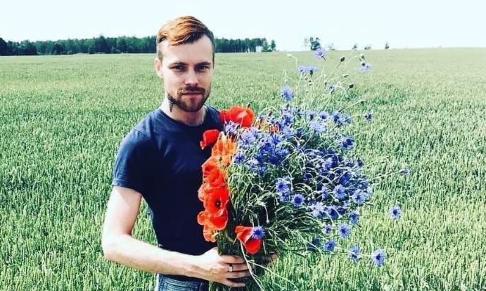 Normunds Kindzulis holds a bouquet of flowers in a field