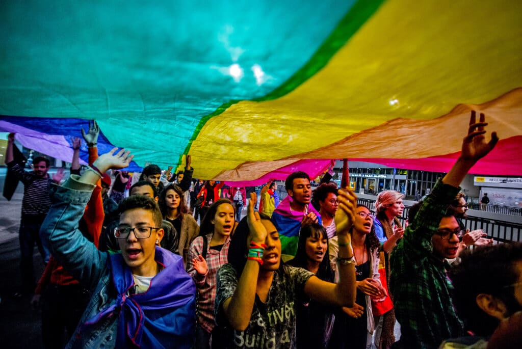 People hold up an LGBT+ Pride flag during a march