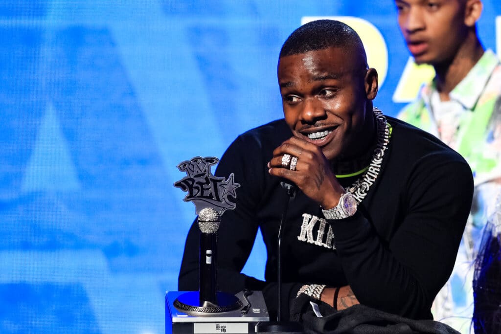 DaBaby speaks in a black sweatshirt onstage at the BET Hip Hop Awards 2019