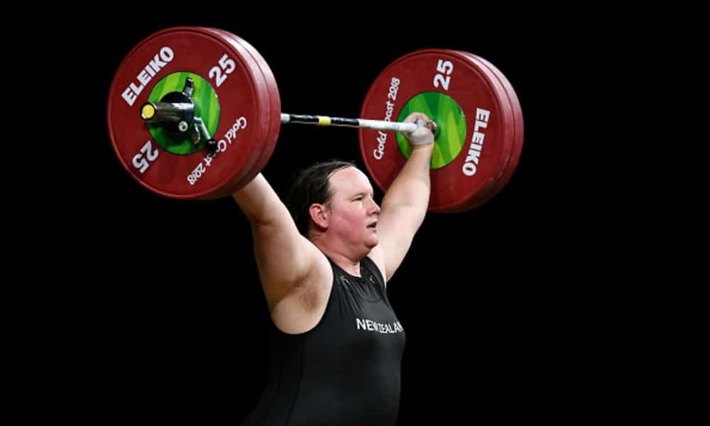 Laurel Hubbard weightlifting at the Commonwealth games with a black background.