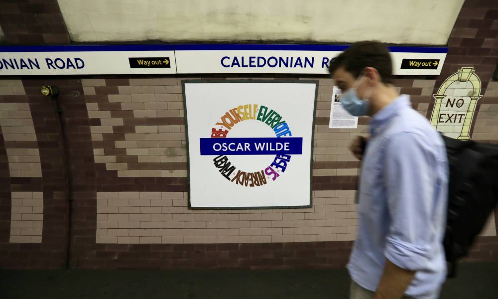 A person walks by the LGBT+ Pride London Underground roundel designed by Amy Lamé at the Caledonian Road station