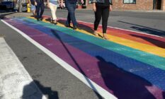 People walk across a rainbow road crossing in Port Colborne, Canada