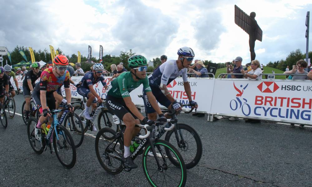 Cyclists seen in front of a sign for British Cycling, the boss of the governing body has recently condemned homophobia and transphobia in the sport