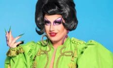 A promotional photo of Drag Race UK series three contestant Choriza May in a green outfit with a beautiful black wig and sharp acrylic nails