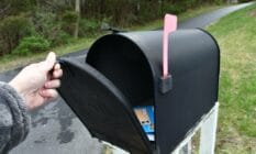 A person opening up a mailbox to illustrate trans and non-binary people from Canada seeing their deadname on voters cards in the mail
