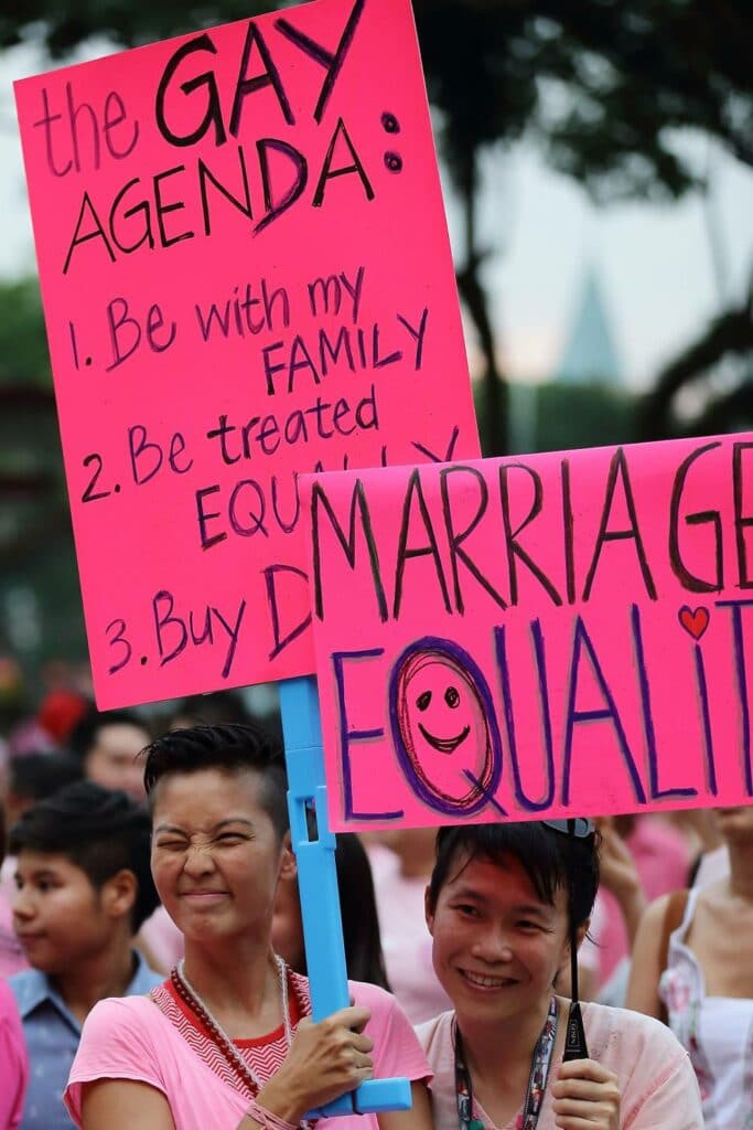 Participants hold up signs supporting Singapore's LGBT+ community