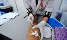 A medical official takes blood from a person for rapid HIV testing
