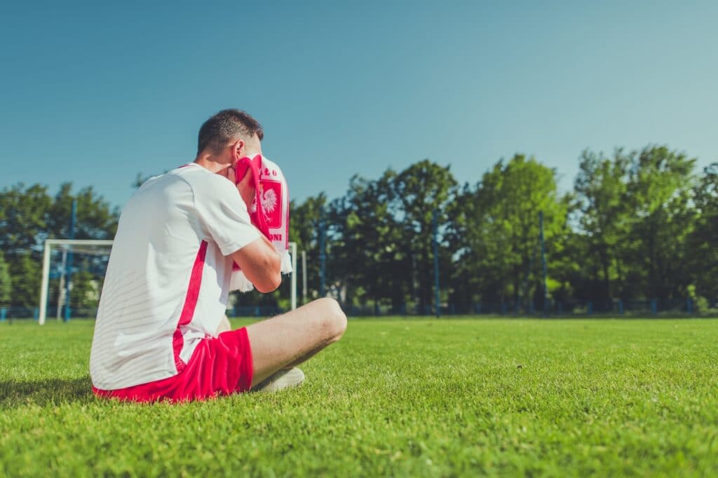 Man sitting on a football pitch crying