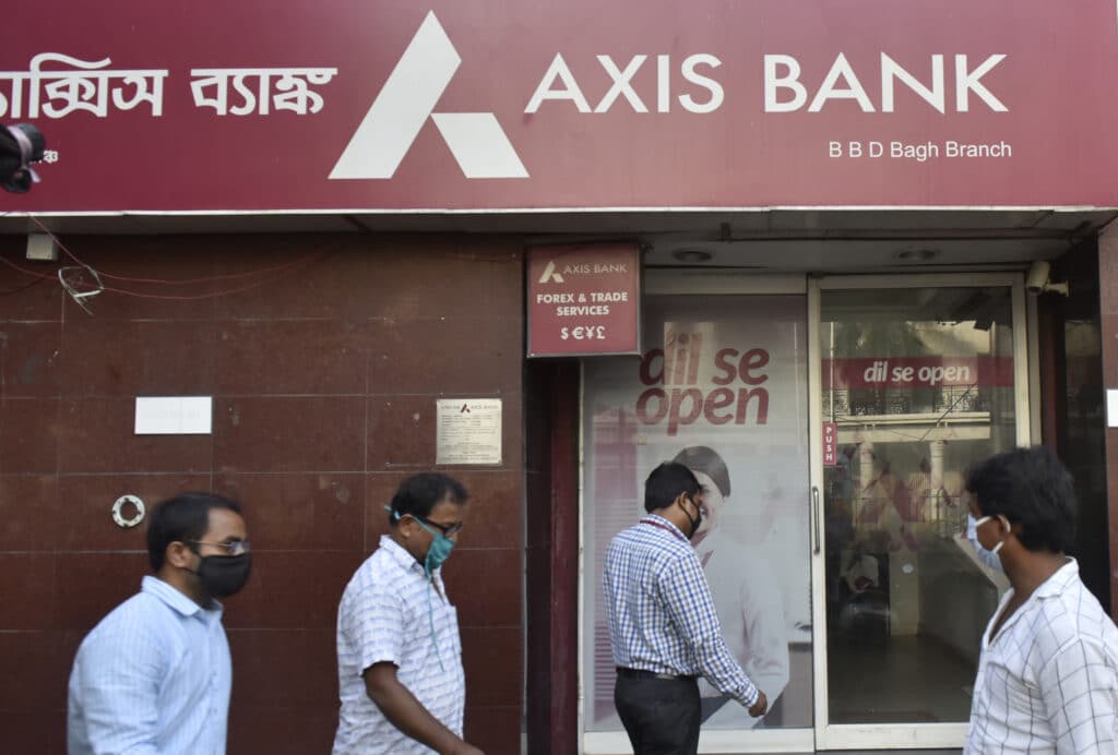 People walk past an Axis Bank in Kolkata, India