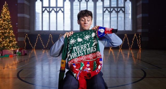 Tom Daley holding up a Merry Christmas jumper