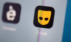 the black and yellow Grindr logo can be seen on the screen of a phone