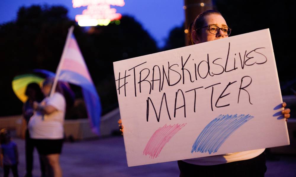 Trans rights advocate holds a sign that reads 'trans kids lives matter'
