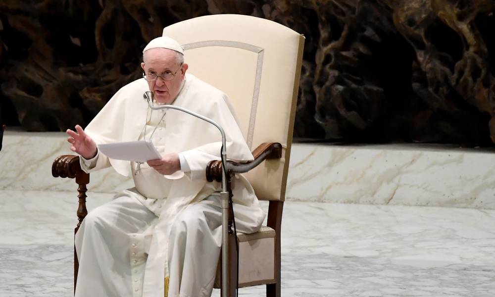 Pope Francis sits in a chair as he addresses attendees during a weekly general audience 